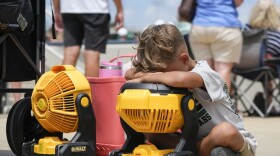 FILE - Braxton Hicks, 7, of Livingston, Texas, holds his face to a portable fan to cool off during the DYB, formerly Dixie Youth Baseball, Little League tournament in Ruston, La., Aug. 9, 2023. The rate Earth is warming hit an all-time high in 2023 with 92% of last year’s surprising record-shattering heat caused by humans, top scientists calculated. (AP Photo/Gerald Herbert, File)