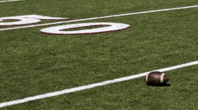 A football on a football field near the 50 yard line.