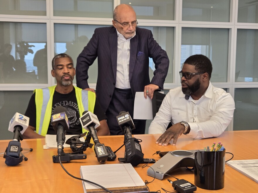 Anthony Wynn (left) is returning to a career as a lineman but needs to accumulate hours, a gargantuan feat after the bridge collapse. Alonzo Key (right), a veteran of 12 years, explains the ways that the collapse has hut workers while their attorney, William "Billy" Murphy, listens in. Photo by Emily Hostaedter/WYPR.