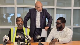 Anthony Wynn (left) is returning to a career as a lineman but needs to accumulate hours, a gargantuan feat after the bridge collapse. Alonzo Key (right), a veteran of 12 years, explains the ways that the collapse has hut workers while their attorney, William "Billy" Murphy, listens in. Photo by Emily Hostaedter/WYPR.