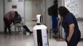 A healthcare worker communicates with a fellow doctor via Laluchy Robotina, a robot designed to aid in the mental health of patients infected with the new coronavirus, in the COVID-19 ward at 20 de November National Medical Center in Mexico City, Friday, Sept. 25, 2020. The 1.4-meter-tall robot that moves around on wheels visiting COVID-19 patients, is equipped with a camera and display screen which allows the patients to visit with relatives and to also communicate with healthcare workers, helping to reduce the risk of infection. (AP Photo/Marco Ugarte)