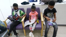 FILE - Siblings Amechi, 7, left, Chizara, 5, center and Kenechi Acholonu, 9, enjoy gifts from the hospital as they wait in the observation area after being inoculated with the first dose of the Pfizer COVID-19 vaccine for children 5 to 11 years at The Children's Hospital at Montefiore, Wednesday, Nov. 3, 2021, in the Bronx borough of New York.  First shots are averaging about 300,000 per day. (AP Photo/Mary Altaffer, File)