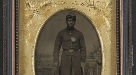 Sergeant Tom Strawn of Company B, 3rd U.S. Colored Troops Heavy Artillery Regiment, with revolver in front of painted backdrop showing balustrade and landscape credit: LOC/Flickr/Creative Commons