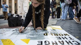 Dinah Landsman, 17, writes on a poster before activists gather and walk through lower Manhattan for the Global Climate Strike protests, Friday, Sept. 23, 2022, in New York. (AP Photo/Brittainy Newman)