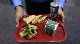 Leonardo Guerra, of Don Pancho Authentic Mexican Foods, holds a school lunch tray, featuring his company's whole wheat tortillas, at the School Nutrition Association conference in Boston, Monday, July 14, 2014. (AP Photo/Charles Krupa)