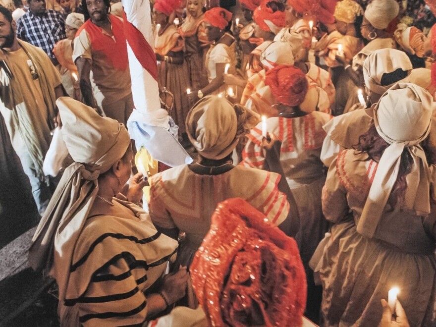 Mambos, or priestesses in the vodou tradition circle a central post, a poto mitan