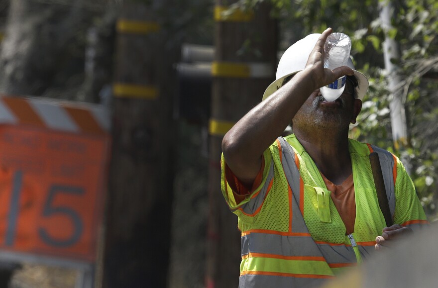 A construction worker drinks water while on a break from working on a street paving crew Friday, Sept. 1, 2017, in Orinda, Calif.  Dozens of cooling centers opened throughout California, schools let students out early and outdoor events were cancelled as temperatures soared from a heat wave expected to last through the Labor Day weekend. (AP Photo/Ben Margot)