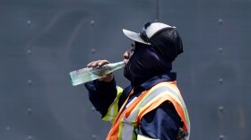 FILE - Standing in the mid-afternoon heat, a worker takes a break to drink during a parking lot asphalt resurfacing job in Richardson, Texas, June 20, 2023. While unrelenting heat set in across Texas this summer, opponents of a sweeping new law targeting local regulations took to the airwaves and internet with an alarming message: outdoor workers would be banned from taking water breaks. Workers would die, experts and advocates said, with high temperatures topping 100 degrees Fahrenheit (38 degrees Celsius) and staying there for much of the past two months. (AP Photo/LM Otero, File)