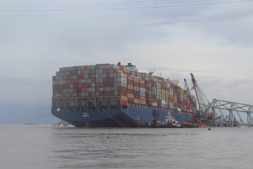 The Dali, the cargo vessel that struck a supportive pylon, causing the Francis Scott Key Bridge to collapse, is pictured with part of the wreckage of the bridge on April 4, 2024. Photo by Scott Maucione/WYPR.