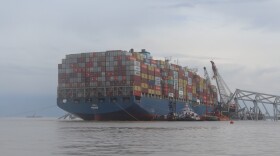 The Dali, the cargo vessel that struck a supportive pylon, causing the Francis Scott Key Bridge to collapse, is pictured with part of the wreckage of the bridge on April 4, 2024. Photo by Scott Maucione/WYPR.