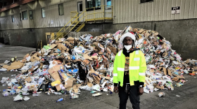 Dondre Grey, a heavy equipment operator at Northwest Transfer Station, posing in front of a heap of single-stream recycling (photo credit: Aaron Henkin / WYPR)