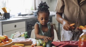 Unrecognizable African American mother and daughter preparing vegetables for lunch in the kitchen