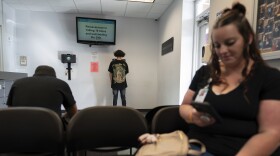 A person signs in, center, as Jesse Johnson of the Family Resource Center, right, waits for client Tyler Baker to complete a random drug test at the Hancock County Adult Probation office in Findlay, Ohio, Thursday, Oct. 12, 2023. Experts say establishing peer support programs to help people in recovery is one way communities should consider using money from settling lawsuits with the drug industry over the toll of opioids. (AP Photo/Carolyn Kaster)