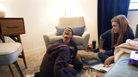 Therapist Sarah Sutton, right, looks on as brothers Ronan Kotiya, 11, left, and Keaton Kotiya, 9, center, laugh during a counseling session in Plano, Texas, Friday, April 8, 2022. Caregiving for their father with ALS is a task that children like Ronan and Keaton take seriously and something that their mom hopes will shape them into empathetic, strong young men. But getting there first involves a daily struggle to balance being a kid with living in a very grown-up world. Sutton has seen the boys regularly for a few years. She's been trying to get them to recognize all the emotions hitting them and realize where they are coming from instead of keeping everything bottled up. (AP Photo/LM Otero)