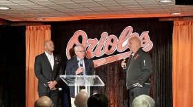 Maryland Gov. Wes Moore and Hall-of-Famer Cal Ripken, Jr., who is part of Rubenstein's ownership group, watch as Baltimore Orioles majority owner David Rubenstein speaks before Opening Day on Thursday, March 28, 2024, in Baltimore. Photo by Rachel Baye/WYPR.