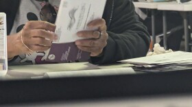 An election judge opens a ballot envelope.