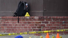 A backpack is seen near evidence markers at the site of a shooting near Edmondson Westside High School, Jan. 4, 2023, in Baltimore. In response to rising youth violence, Baltimore leaders are ramping up efforts to de-escalate conflicts between young people and protect students going to and from school. (AP Photo/Julio Cortez)