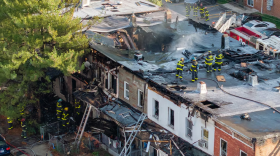 Baltimore City firefighters mop up a five-alarm blaze that affected multiple rowhomes in North Baltimore. (Jerry Jackson/The Baltimore Banner)