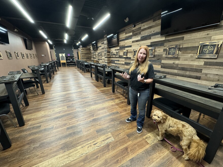 Worth-A-Shots owner Donna Worthy and her mini-doodle Remi show off her store's training room. Photo by Rachel Baye/WYPR.