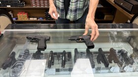 Theodore Daniels displays two of Worth-A-Shot's bestselling handguns, the Glock 43X and the Sig Sauer P-365 Rose, a special edition marketed to women. Photo by Rachel Baye/WYPR.